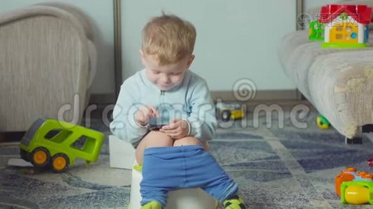 可爱的男孩带着智能手机在房间里的厕所训练。视频