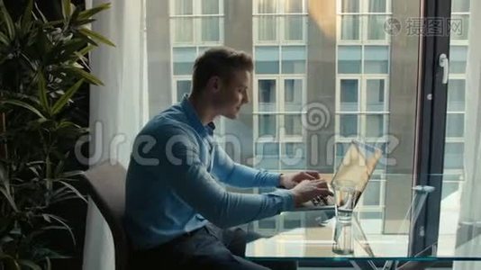 英俊的年轻人在室内用笔记本电脑工作。视频