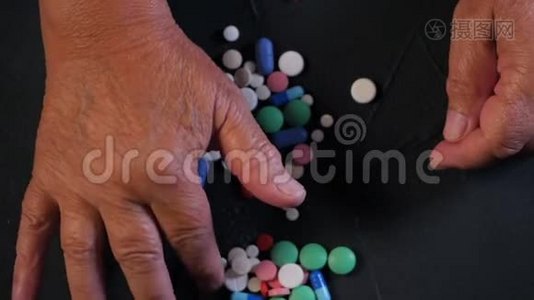 祖母在家里的黑桌上数着五颜六色的药片。 老年概念，药物，治疗。 最后报告视频