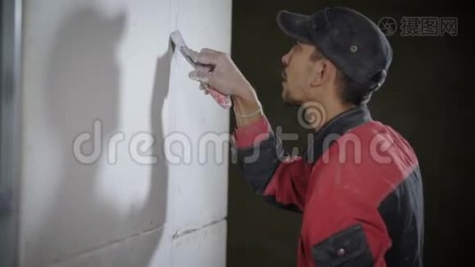 收缩工人正在用铲刀在平面上铲平墙壁。视频