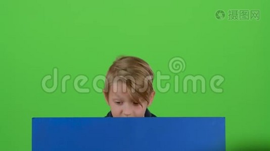 少年站起来，在绿色屏幕上的一块木板上表演视频