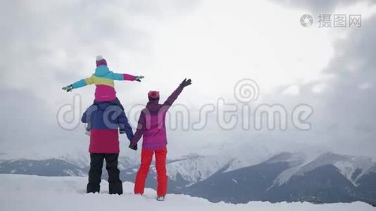 幸福的家庭在山上享受寒假。 家庭滑雪度假。 人们观察山景。视频