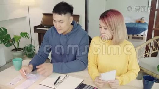 年轻时强调，亚洲夫妇管理财务，在现代家庭使用笔记本电脑和计算器审查他们的银行账户。视频