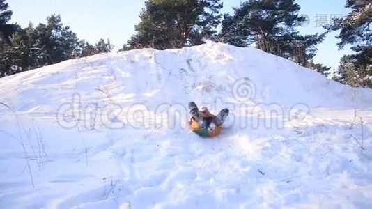 快乐的少女在白雪覆盖的森林背景下的冬天公园里，带着雪滚下山，一家人在一个温暖的小屋里视频