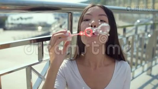 漂亮的亚洲女孩站在桥上吹泡泡视频