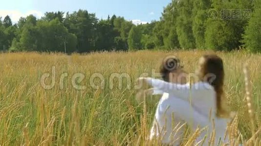 一个年轻的女人和一个穿着白色西装的男人逃跑，见面拥抱。 在阳光明媚的日子里，在一片麦田里。视频
