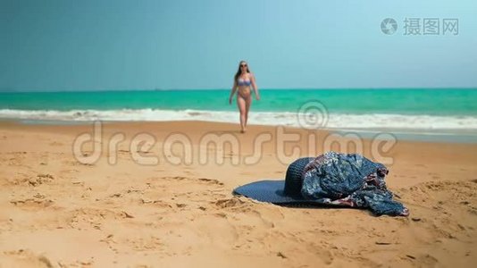 小女孩从海里出来，从沙子里举起衣服。 中弹。 斯隆运动视频
