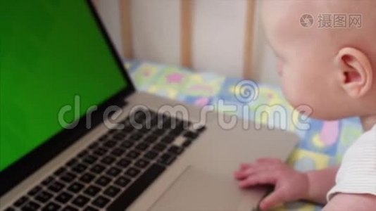 6个月大的男孩在床上玩手提电脑的慢镜头画像视频