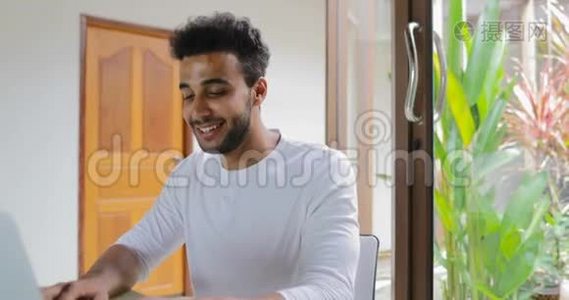 年轻男子在家中使用笔记本电脑坐桌，西班牙裔男子打字视频