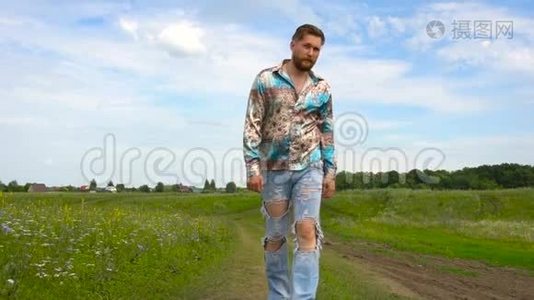 夏天，一个留着胡子穿着破牛仔裤的男人在田野里散步视频