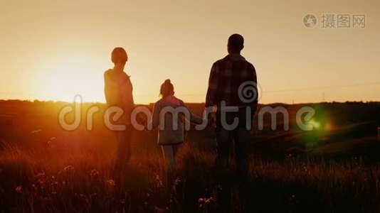 年轻的家庭期待着日落的地平线。 妈妈，爸爸和女儿在一起视频