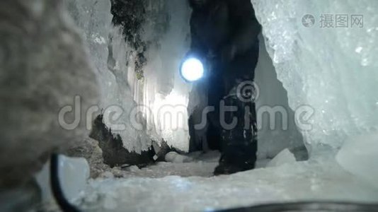 在贝加尔湖冰洞旅行的人。 去冬岛旅行。 背包客正在冰窟散步。 旅行者看着视频