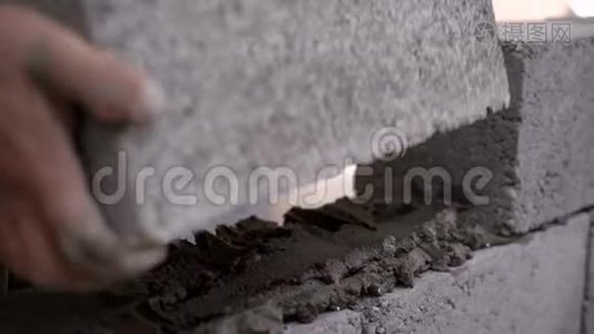 一个建筑工人在工地上工作并砌墙的特写镜头。视频
