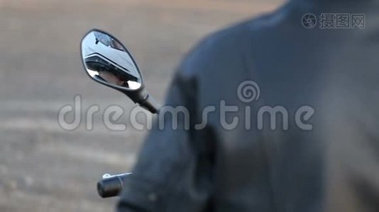 一个穿黑色皮夹克的年轻人坐在摩托车上，在秋日日落前准备好白色头盔视频