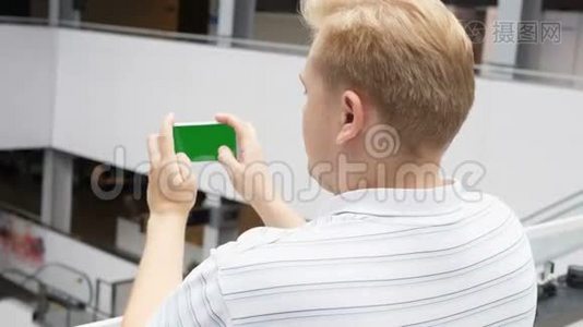 智能手机与绿色屏幕男性手在景观模式下玩游戏。 易于定制的绿色屏幕。 看男人视频