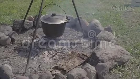 在木桩旁的树林里准备热的新鲜食物。 一个盛有热鲜汤、炖菜或粥的大锅视频