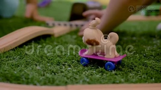 小朋友的手在房间里的紫色滑板上玩塑料玩具狗。视频