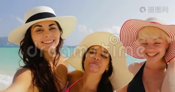 沙滩上的女孩在手机上自拍，夏日假日里比基尼和草帽里的快乐女人视频