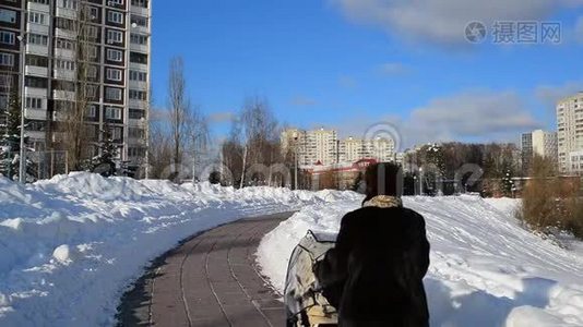 带着婴儿车的女人走在俄罗斯莫斯科的林荫大道上。视频