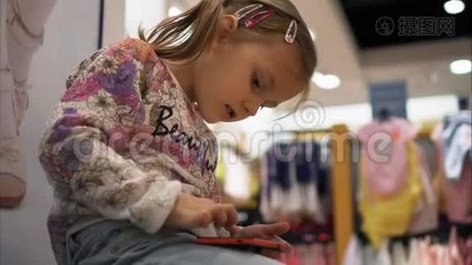 小女孩正在商店里用智能手机玩游戏视频