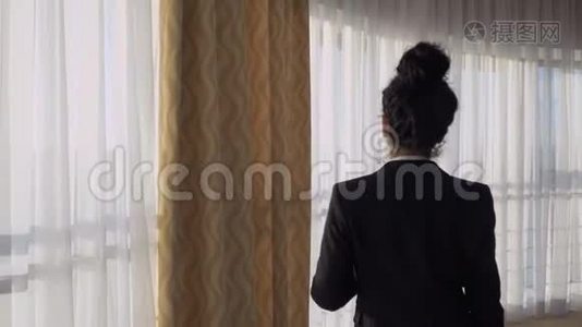 女商人在酒店房间的窗户附近散步视频