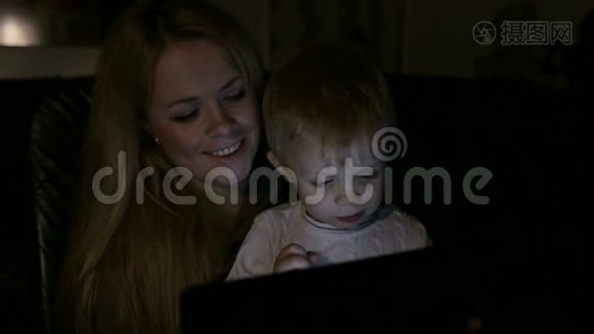母亲和孩子晚上在家玩平板电脑。视频