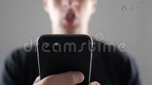 愤怒的人用智能手机。 手里拿着智能手机的愤怒的吼叫男人视频