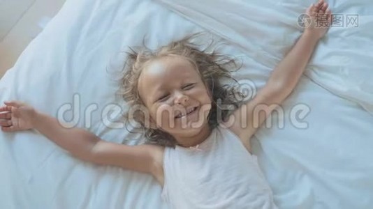 可爱的童女躺在床上，看着相机，笑着的肖像。视频