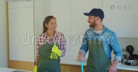 一对夫妇的肖像，作为一名职业清洁工，穿着制服，站在一起，在室内使用清洁工具。视频