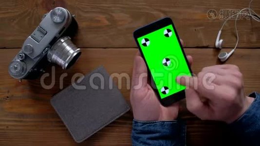 摄影师使用智能手机，绿色屏幕在木桌上。视频