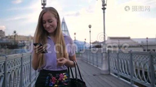 年轻女商人带着电话走在桥上视频