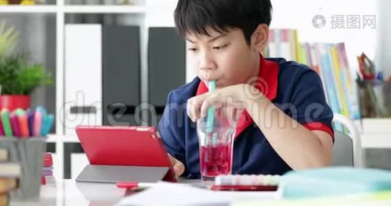 亚洲男孩在家里在平板电脑上喝酒和观看。视频