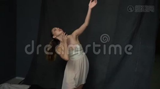 拍摄过程中，一个留着长发和一件白色连衣裙的女孩正在演播室里跳舞，动作缓慢视频