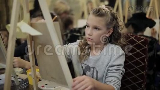 美丽的女孩金发少年在一所艺术学校画一幅画。视频