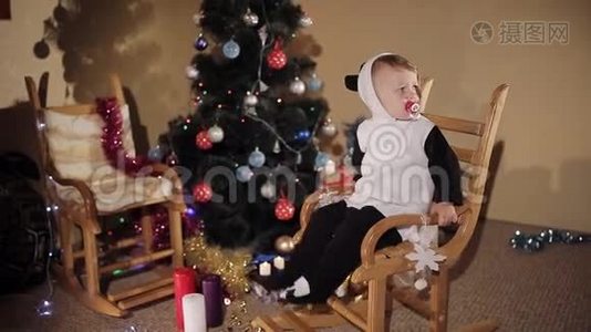 在圣诞树和蜡烛的背景下，孩子在摇椅上摇摆。 圣诞节的气氛。视频