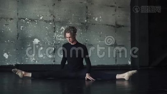 男芭蕾舞演员坐在地上的绳子上做伸展运动视频
