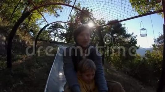 一对父子在秋林中乘坐高山过山车的慢镜头视频