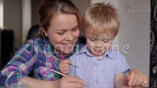 可爱的小男孩和他妈妈在家画画。视频