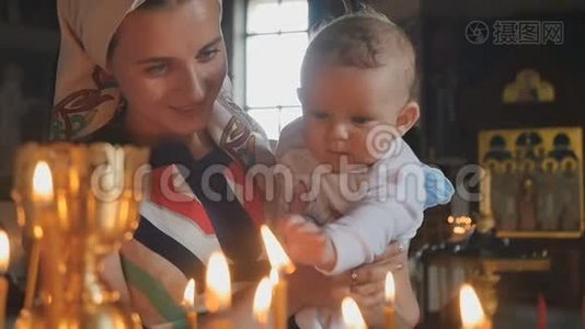 年轻的母亲带着孩子慢慢地观察教堂里燃烧的蜡烛视频