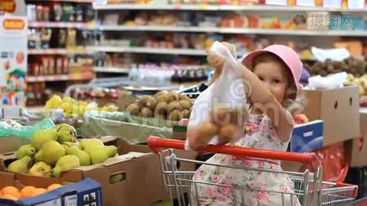 商店里的小女孩选水果。杂货超市和购物车视频