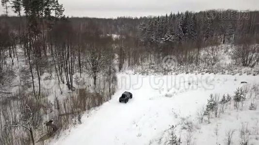 一辆6x6越野车的鸟瞰图，它在冬天森林里的雪覆盖的道路上行驶视频