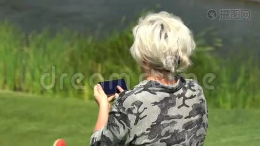坐在草地上的女人用手机视频