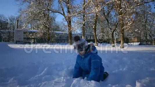 在雪中玩耍的无忧无虑的男孩。儿童寒假慢动作游戏。冬季风雪游戏视频