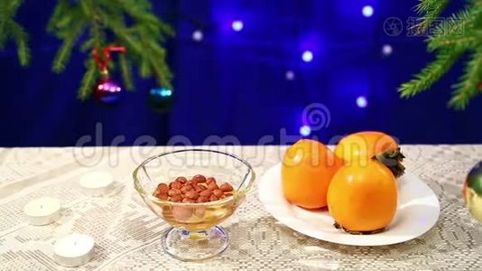 桌上放着坚果、蜂蜜和柿子，放着一棵装饰`圣诞树和牧人的膀胱视频