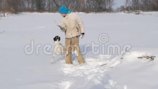 男孩少年在雪地里和狗玩得很开心。视频