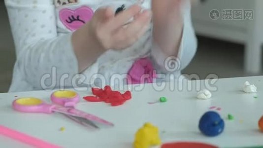 一个小女孩玩橡皮泥，用手滚球，桌面上有数字和彩色铅笔视频