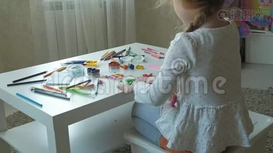 一个小女孩玩橡皮泥，用手把它卷起来，桌面上有数字和彩色铅笔视频
