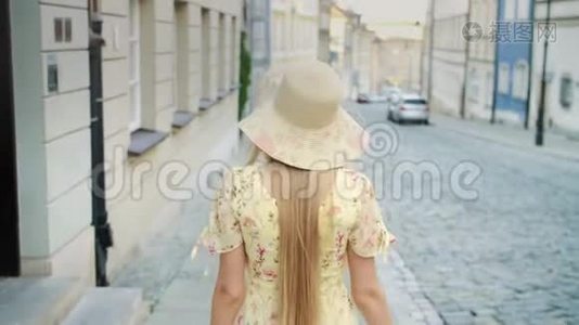 微笑的女人走在街上。 穿着白色帽子的开朗漂亮的女人在城里散步时回头看相机。视频