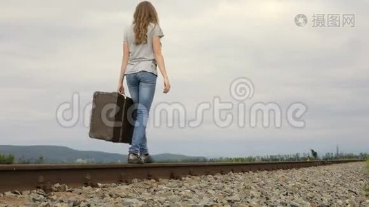 带着手提箱在铁路上行走的少女。视频