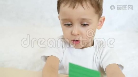 一个孩子正在玩彩色积木，坐在白色背景的桌子旁，动作缓慢视频
